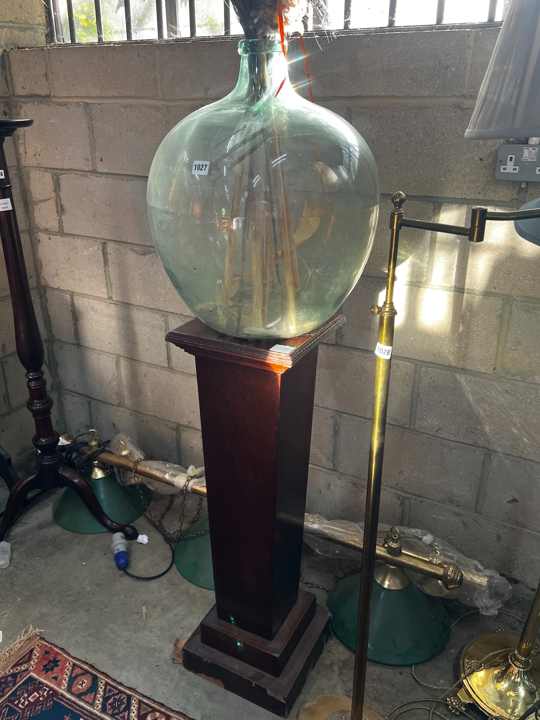 An early 20th century oak pedestal and a green glass carboy, combined height 150cm